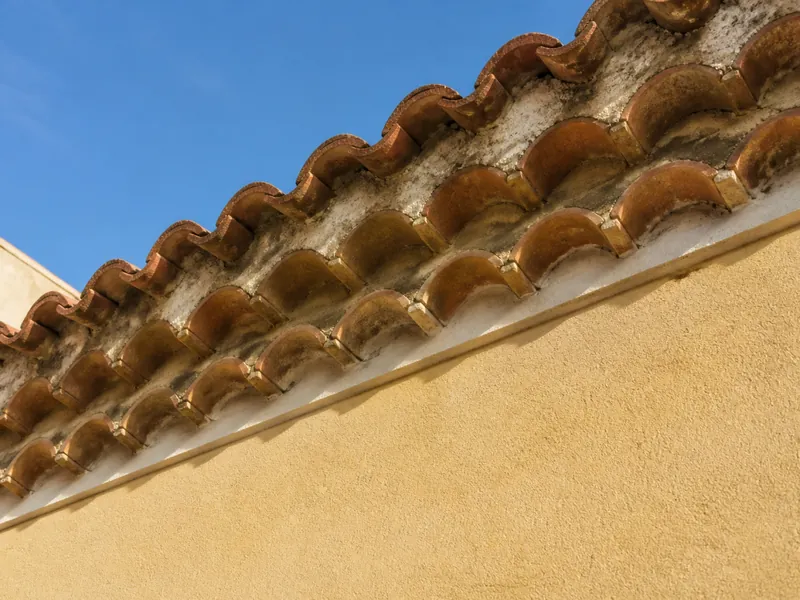 Génoise de tuiles sous l’avancée d’un toit à façade ocre